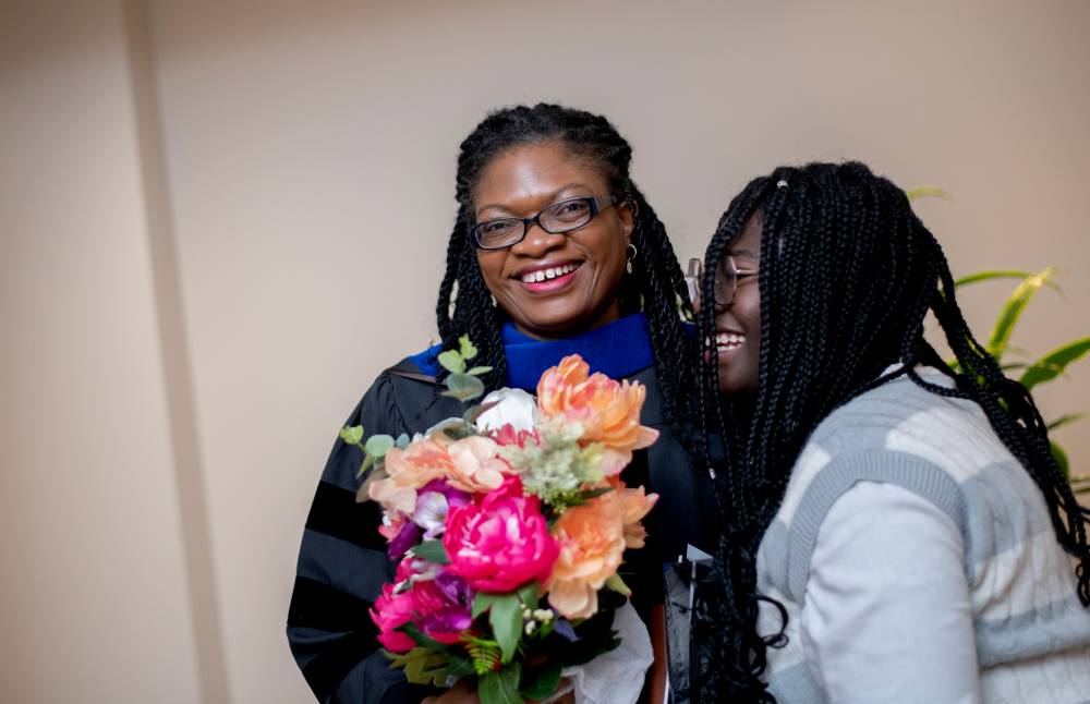 Faculty awardee smiling with a friend holding flowers